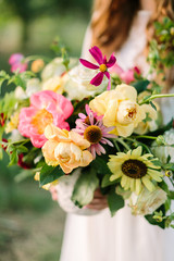 bouquet, people, flower holidays , gift and floral arrangement concept - close up of beautiful summer bouquet in hands of young woman, holding vase at nature background, art decoration work, vertical