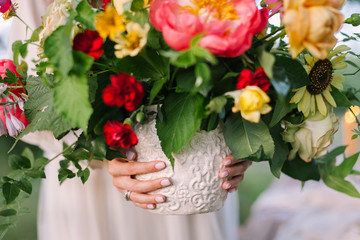 bouquet, people, flower holidays , gift and floral arrangement concept - beautiful bouquet of fresh summer flowers roses, peonies, daisies, carnations in a white vase in the hands of a young girl