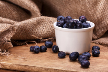 Pot of blueberries on a rustic background