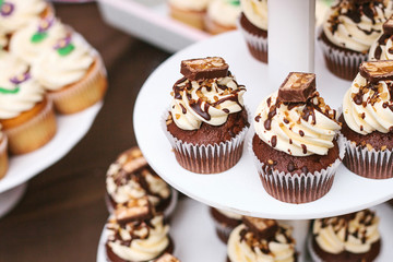 Freshly baked chocolate cupcakes with butter cream, nuts and chocolate top view. Dessert for the holidays
