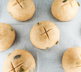 Pumpkin seed buns proofing on baking paper at close-up