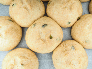 Pumpkin seed buns proofing on baking paper at close-up