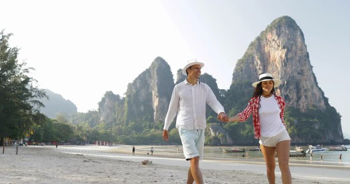 Couple Walking On Beach Holding Hands Talking Young Man And Woman Tourists On Vacation Slow Motion 60