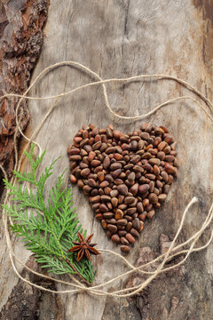 Unshelled pine nuts in form of heart on aged wood