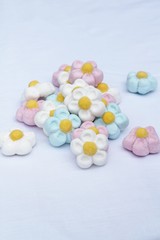 A pile of sweet flower marshmallow treats , candy in pink, blue, white and yellow , shallow depth of field