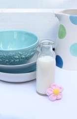 Kitchen table blue crockery with teatime bottle of milk and a pink marshmallow , a spotty jug 