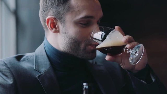 Males holding bottles of beer, mug of beer and drink it with pleasure, laugh surprised with the result and continue to have a good time. Friends forever, bachelor party. Males club, men&rsquo;s style.
