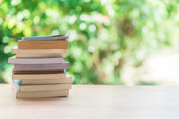 Book stack on wooden table with blur background