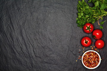 Fresh basil and cherry tomatoes on the dark background with spices. Top view with copy space.