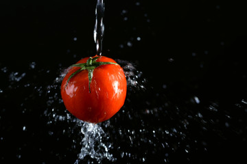 Tomato in splashes of water on a black background