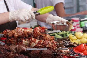 Seller at the counter with shish kebab and vegetables. Food