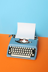 Vintage blue typewriter over a pastel background.