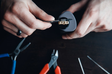 male master installs a coyle. Spiral for electronic evaporator and cigarette. Vape, vaping. Pliers,...