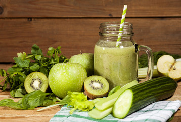 Freshly blended green smoothie in glass jar with straw. Wooden background.