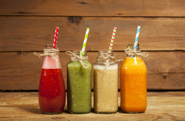 Obraz na płótnie Canvas Assortment of fruit and vegetable smoothies in glass bottles with straws
