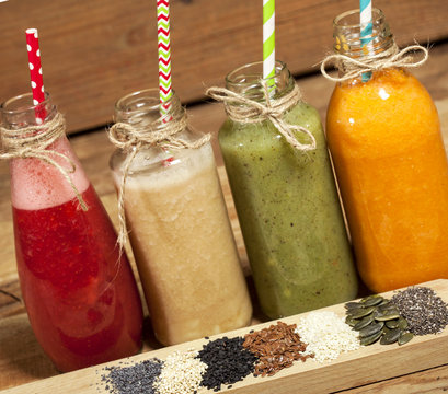 Assortment of fruit and vegetable smoothies in glass bottles and seeds
