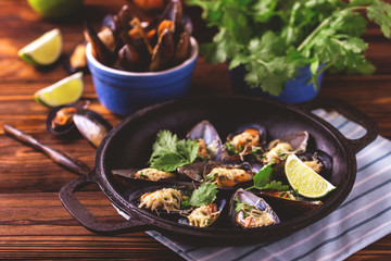 Baked shellfish mussels with cheese, cilantro and lime