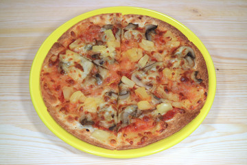 Vegetarian pizza served on a yellow plate on wooden table 