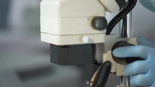Lab worker observing in microscope effect of growth hormone on germinated crops