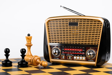 radio receiver in retro style with chess pieces on chessboard and white background