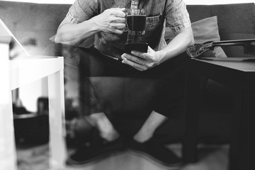 hipster hand using smart phone,digital tablet docking keyboard,coffee cup, payments online business,sitting on sofa in living room,work at home concept