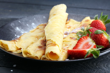 Crepes with jam, strawberries and sugar powder. Homemade pancakes, delicious breakfast