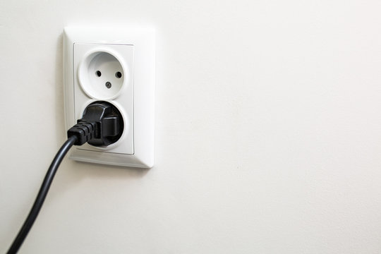 European white electrical outlet socket and black cable on white wall