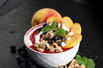breakfast smoothie bowl with blueberries, peach and granola