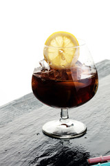 Softdrink with ice cubes, lemon and straw in glass