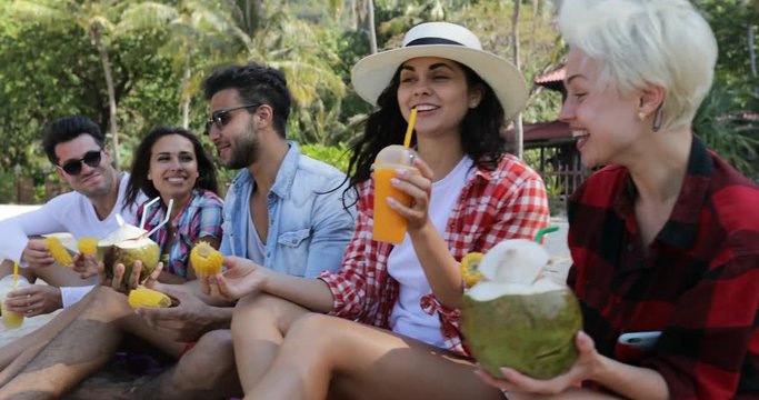 People Eat Tropical Fruits And Drink Coconut Cocktails Talking Sit Over Palm Trees, Happy Men And Women Tourists Tasting Exotic Food Slow Motion 60