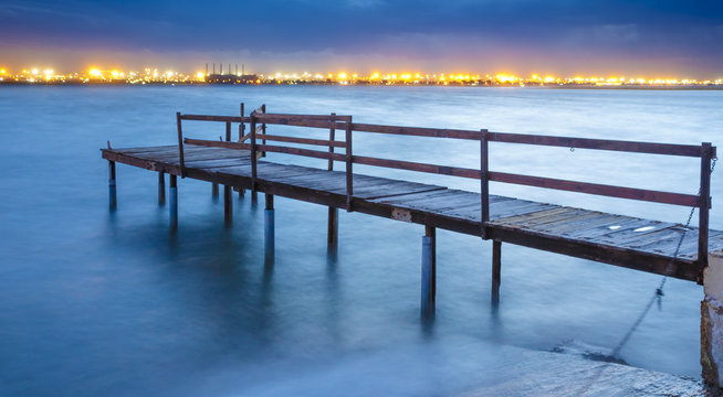 Old Jetty on a River with City Lights in the Background