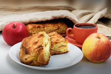 Apple pie charlotte, ripe apples and a cup of coffee on the table