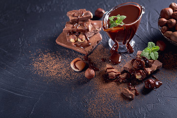 Homemade hazelnut spread or hot chocolate in glass bowl with nuts and chocolate bar.