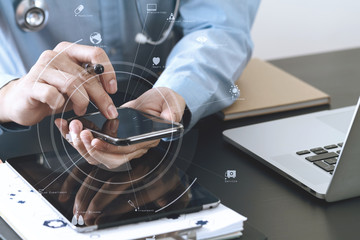 smart medical doctor working with smart phone and stethoscope and laptop and digital tablet computer on dark wooden desk