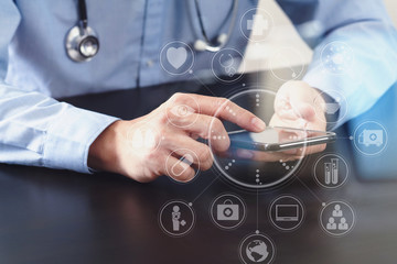 close up of smart medical doctor working with smart phone and stethoscope on dark wooden desk with virtual icon diagram