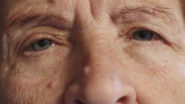 sad old woman opens her eyes,close up portrait
