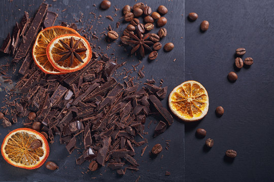 Dark chopping chocolate, black roasted coffee beans, dried lemon slices on dark background
