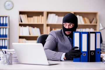 Criminal businessman with balaclava in office