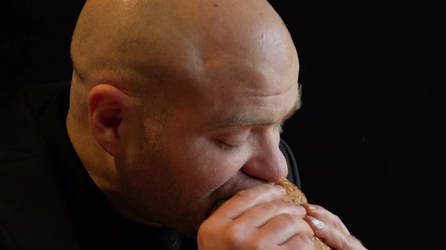 profile of bald  hungry man grabs a burger voracious