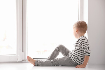 Cute little boy sitting on windowsill