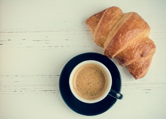 Cup of espresso coffee and fresh baked croissant