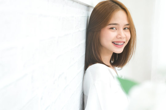 copy space portrait of smiling asian young woman put on the braces, on white background