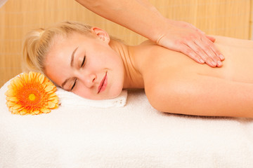 Fototapeta na wymiar Beautiful blonde woman enyoing massage treatment in sap salon