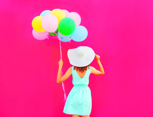 Happy woman holds an air colorful balloons is having fun on a pink background