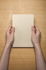 Obraz premium woman hand hold a old book on the wood table(background)