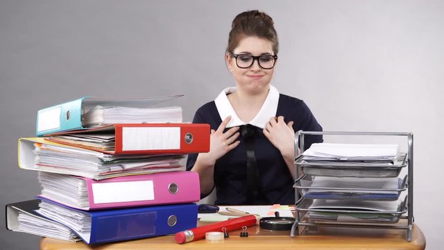 Woman working in office. Humour. Secretary with many documents folders bills on her desk wearing geek nerdy glasses making funny face expression, looking foolish. Workplace, 4K ProRes HQ codec