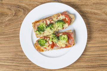 Fototapeta na wymiar open sandwich with prosciutto, mozzarella and tomatoes on kitchen table, shallow focus