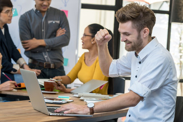 Fototapeta premium Businessman working in success action with computer over the photo blurred of Group Of Asian and Multiethnic Business people with casual suit in the modern Office, people business group concept