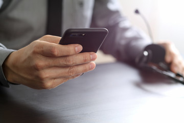 businessman using VOIP headset with mobile phone and concept communication call center on wooden desk