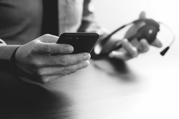 businessman using VOIP headset with mobile phone and concept communication call center on wooden desk
